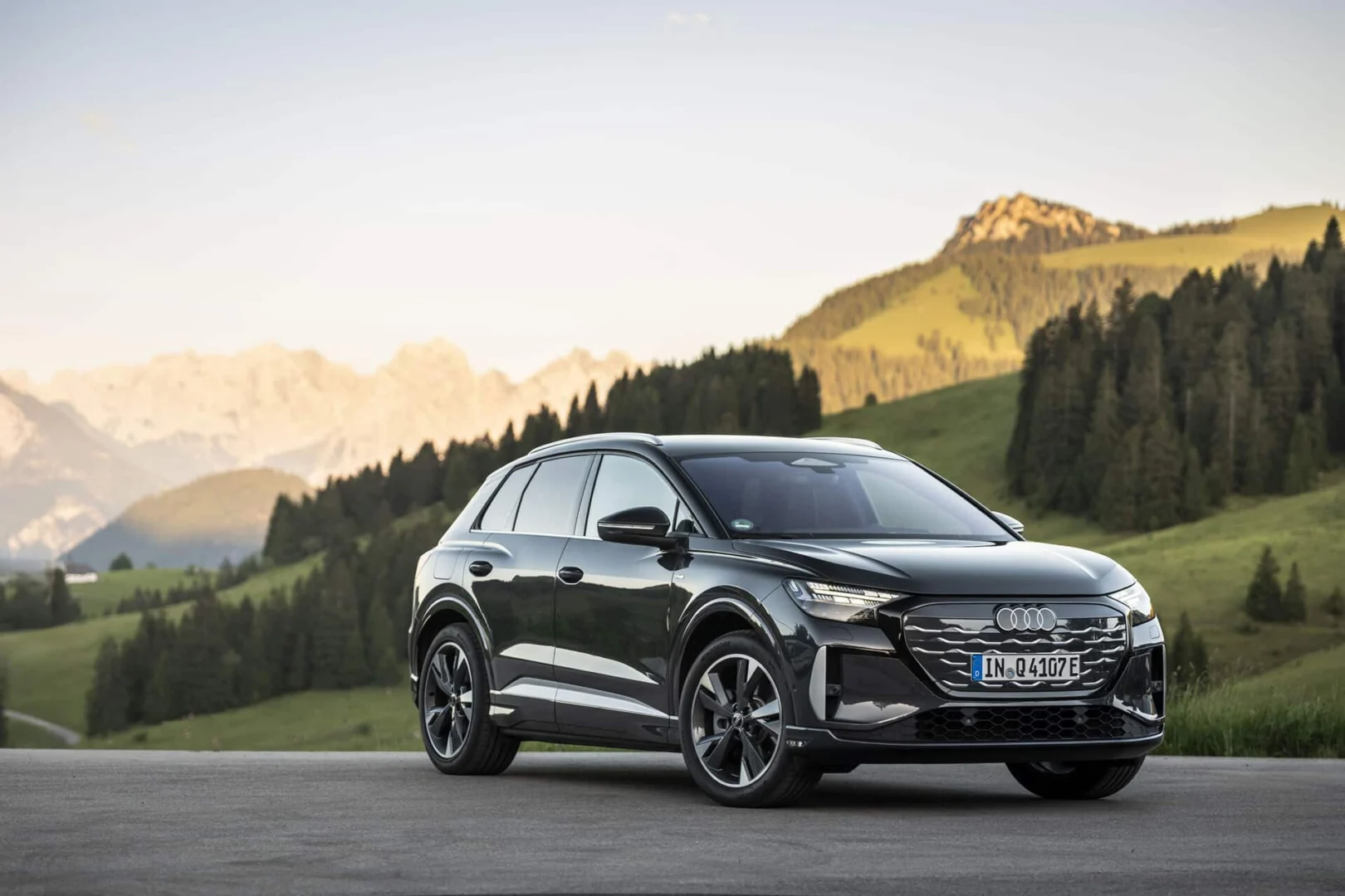 The right car for any situation: the Audi Q4 e-tron takes to the streets - Audi Q4 SUV e-tron in Tamboragrey, outdoor static shot, exterior, three-quarter front view set against an alpine landscape.