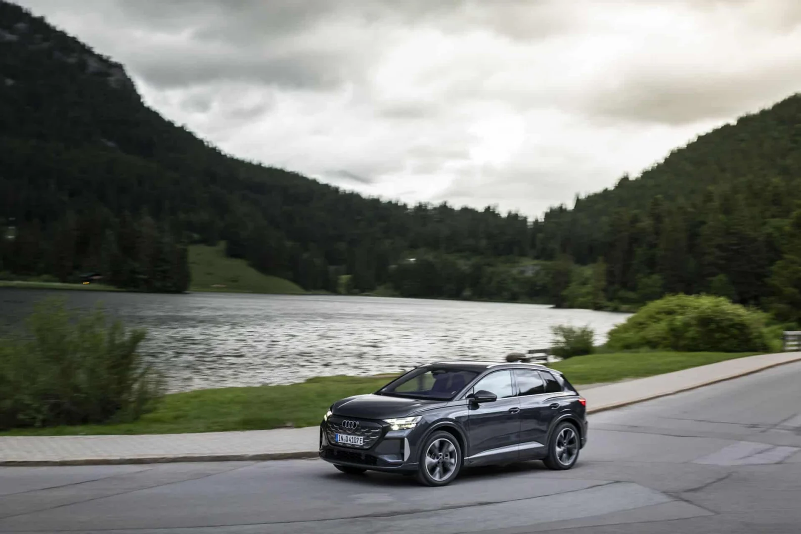 The right car for any situation: the Audi Q4 e-tron takes to the streets - Audi Q4 SUV e-tron in Tamboragrey, outdoor driving shot, exterior, side view along a lakeside.