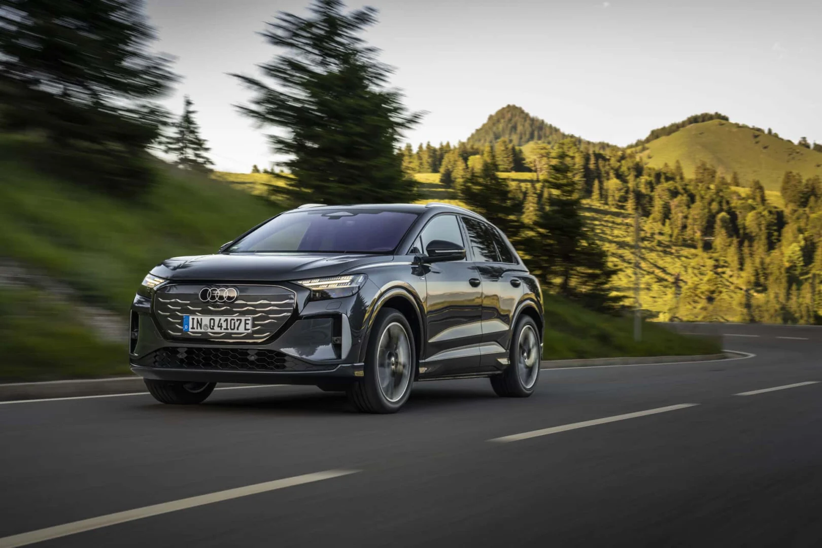 The right car for any situation: the Audi Q4 e-tron takes to the streets - Audi Q4 SUV e-tron in Tamboragrey, outdoor driving shot, exterior, three-quarter front view on a winding road in an alpine landscape.
