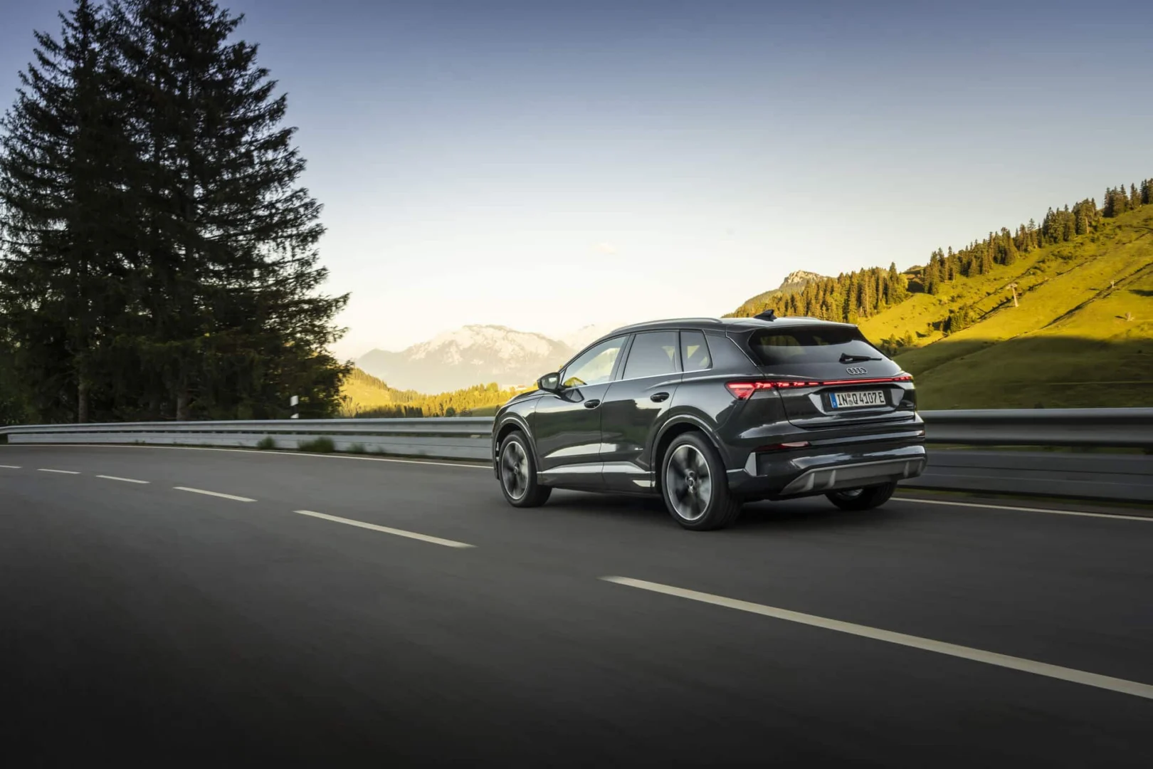 The right car for any situation: the Audi Q4 e-tron takes to the streets - Audi Q4 SUV e-tron in Tamboragrey, outdoor driving shot, exterior, rear three-quarter view in an alpine landscape.
